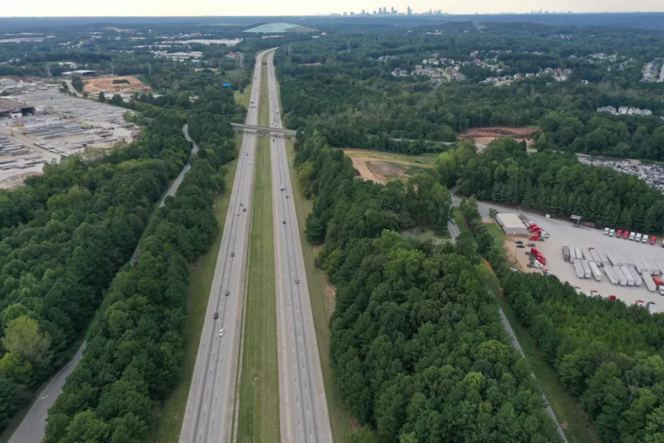 Aerial view of freeway cutting through green forest in Clayton County, Georgia